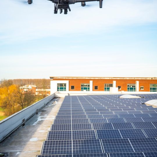 a large black object flying over a building
